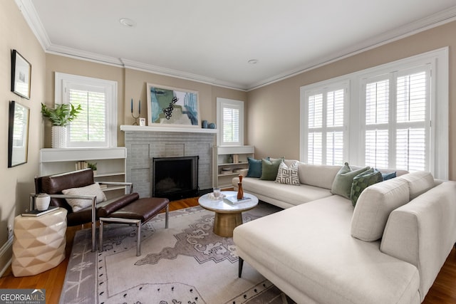 living room with a brick fireplace, plenty of natural light, ornamental molding, and wood finished floors