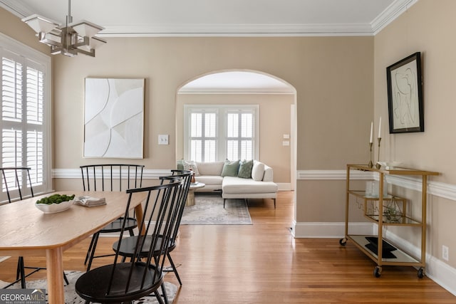 dining space with arched walkways, a healthy amount of sunlight, and wood finished floors