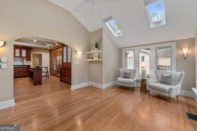 sitting room featuring arched walkways, high vaulted ceiling, visible vents, and a wealth of natural light
