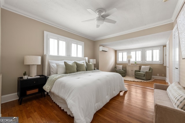 bedroom featuring ornamental molding, wood finished floors, baseboards, a wall mounted AC, and a ceiling fan