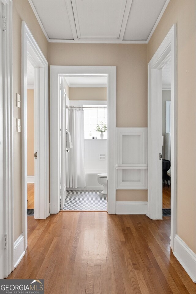 corridor with attic access and wood finished floors