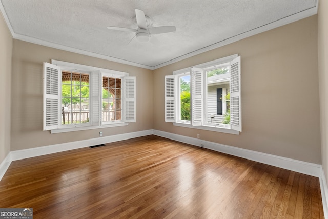 unfurnished room with crown molding, baseboards, visible vents, and wood finished floors