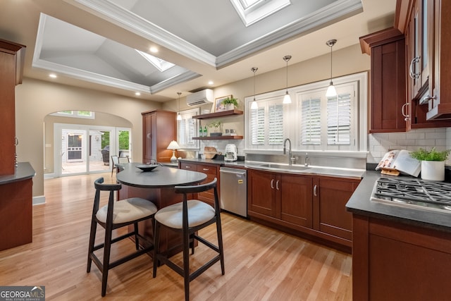 kitchen with dark countertops, a sink, stainless steel appliances, a wall mounted AC, and ornamental molding