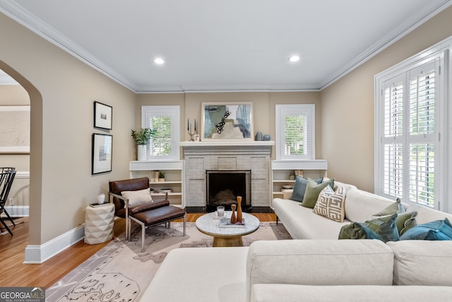 living room featuring arched walkways, ornamental molding, and light wood finished floors