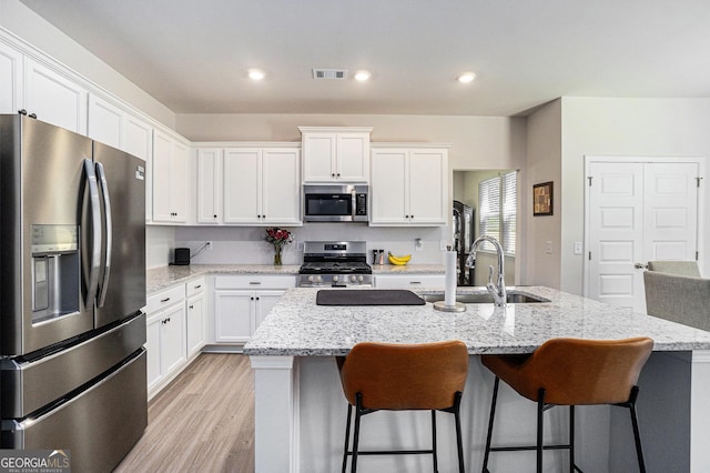 496 River Run Dr, Dallas, GA 30132 - kitchen featuring appliances with stainless steel finishes, white cabinets, a kitchen breakfast bar, light wood finished floors, and recessed lighting