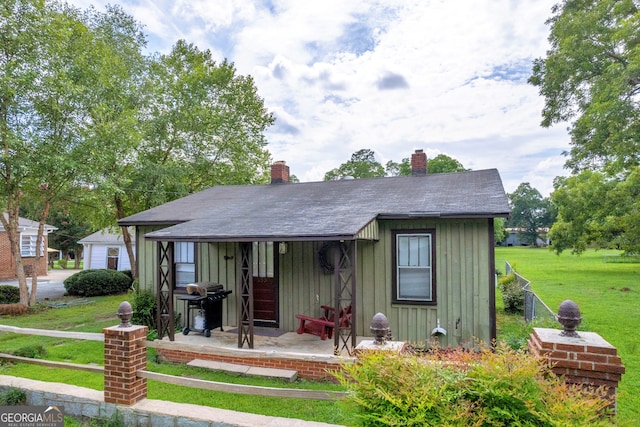 157 Hartwell St, Royston, GA 30662 - view of front facade featuring roof with shingles, fence, a front lawn, board and batten siding, and a chimney