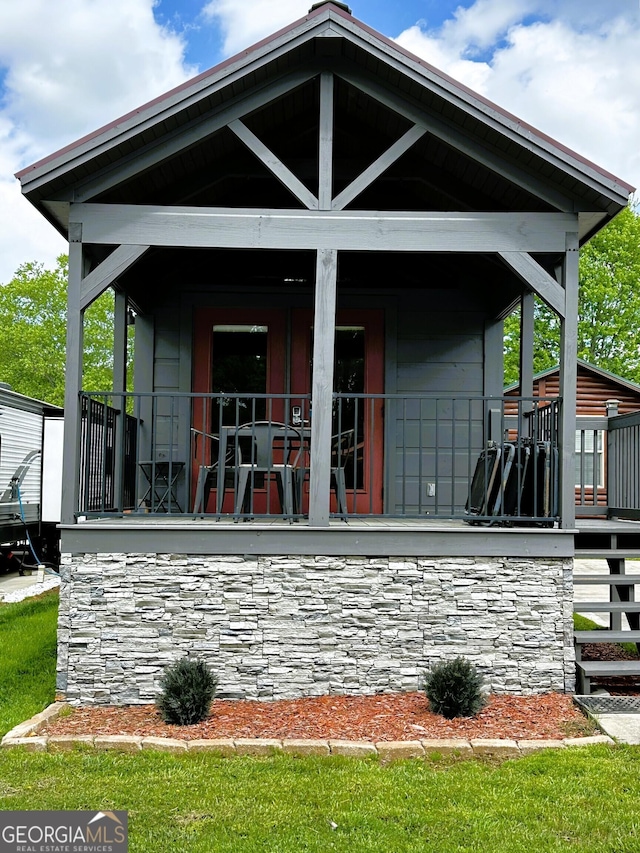 rear view of property with a porch and stone siding