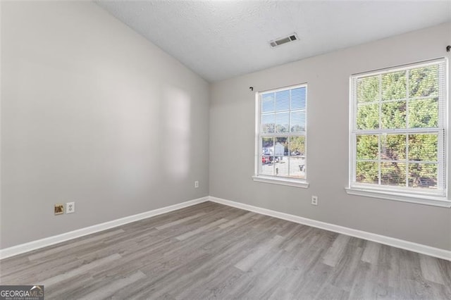 6099 Camden Forrest Cv, Riverdale, GA 30296 - unfurnished room featuring a textured ceiling, visible vents, vaulted ceiling, wood finished floors, and baseboards