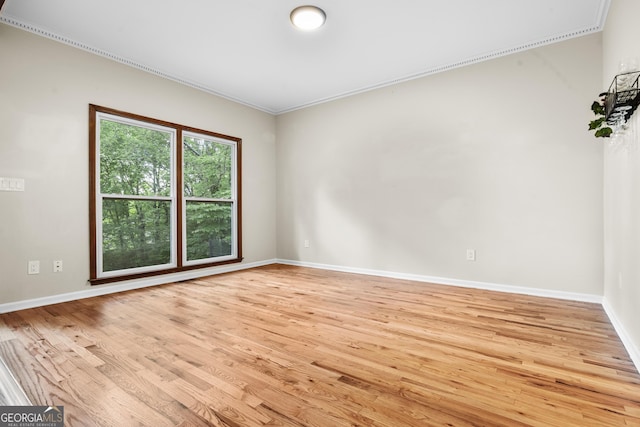 empty room featuring crown molding, baseboards, and light wood-type flooring