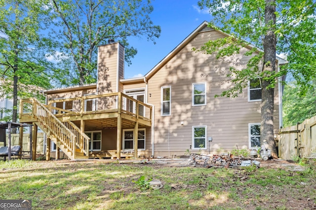 rear view of house featuring fence, stairs, a chimney, and a deck