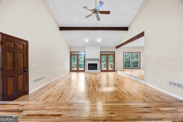 unfurnished living room featuring visible vents, ceiling fan, wood finished floors, and beam ceiling