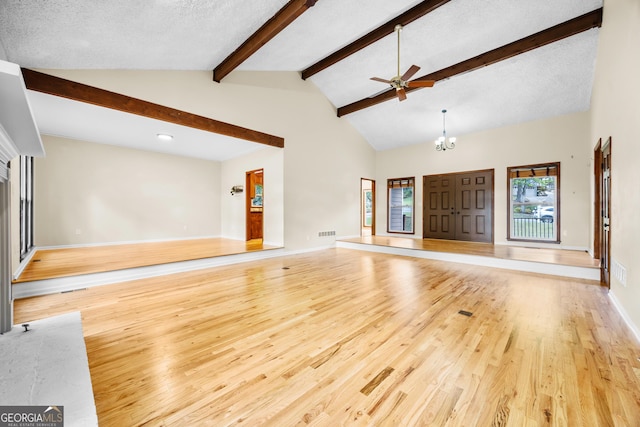 unfurnished living room with visible vents, wood finished floors, beamed ceiling, baseboards, and ceiling fan with notable chandelier