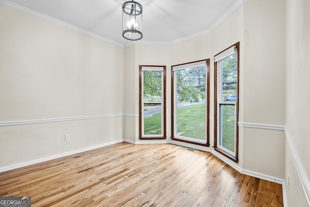 spare room featuring baseboards, ornamental molding, wood finished floors, and a notable chandelier