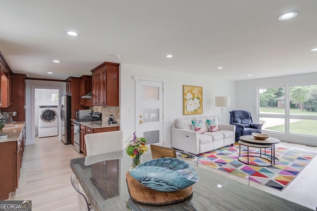 living room with recessed lighting, washer and clothes dryer, and light wood-type flooring