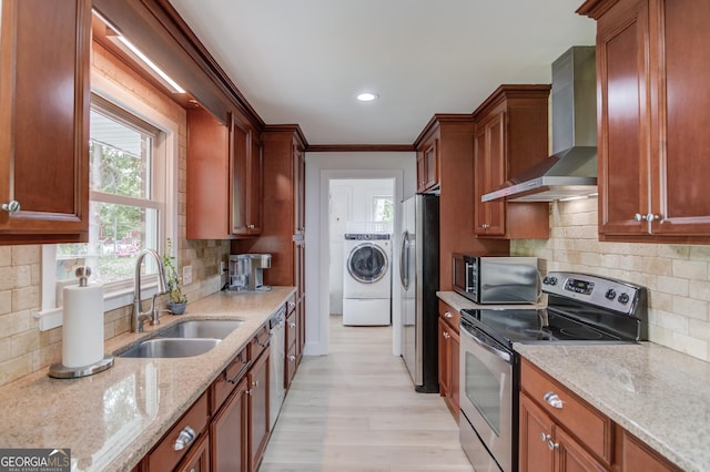 kitchen with decorative backsplash, wall chimney range hood, a sink, independent washer and dryer, and stainless steel appliances