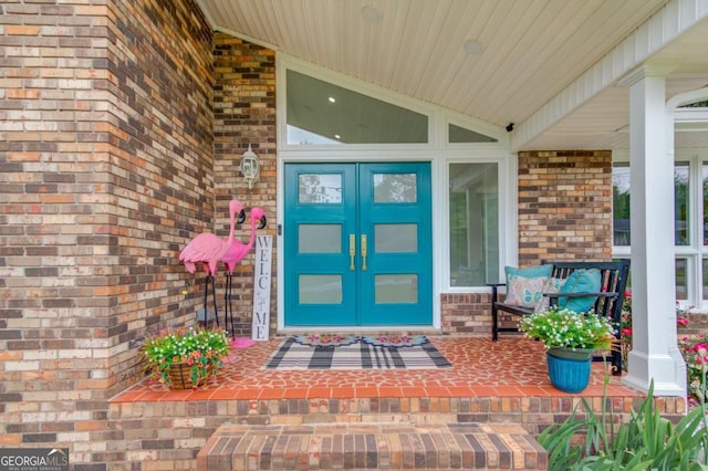 view of exterior entry featuring covered porch and brick siding