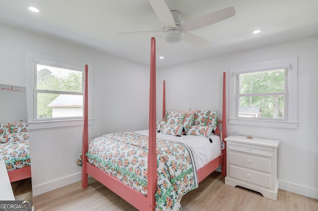 bedroom featuring baseboards, multiple windows, and light wood finished floors