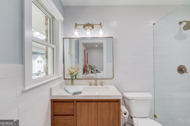full bath with vanity, a healthy amount of sunlight, toilet, and tile walls