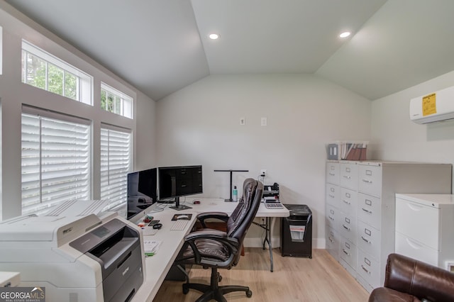 office space with light wood-style floors, baseboards, an AC wall unit, and vaulted ceiling