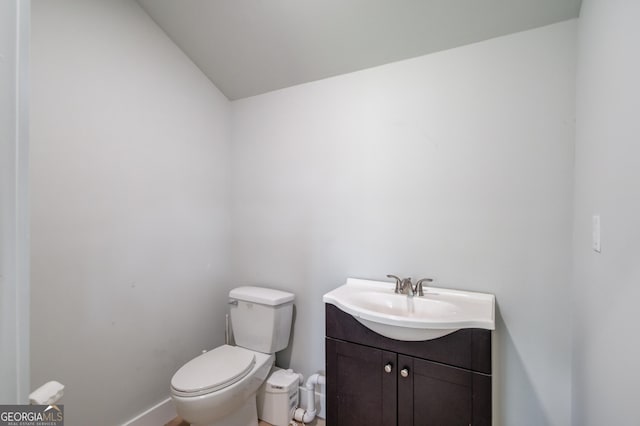 half bath featuring toilet, baseboards, lofted ceiling, and vanity