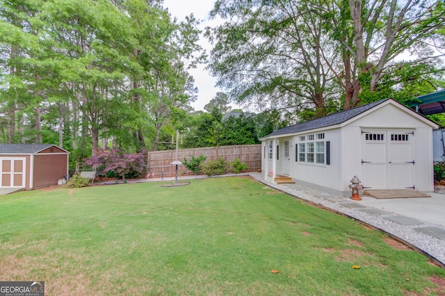 view of yard featuring a detached garage, fence, an outdoor structure, and a storage unit