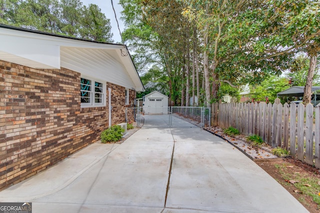 view of property exterior featuring fence, an outdoor structure, and concrete driveway
