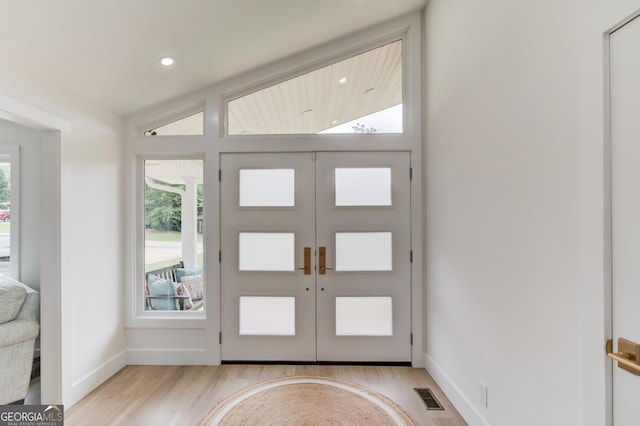 foyer featuring visible vents, baseboards, lofted ceiling, recessed lighting, and light wood-style flooring