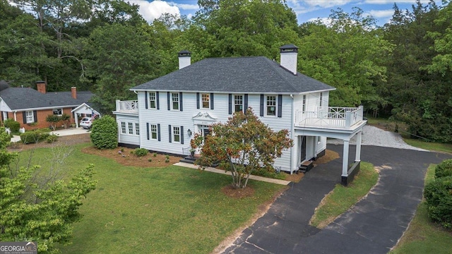 6104 Floyd St NE, Covington, GA 30014 - colonial home featuring driveway, a chimney, a balcony, a front yard, and roof with shingles