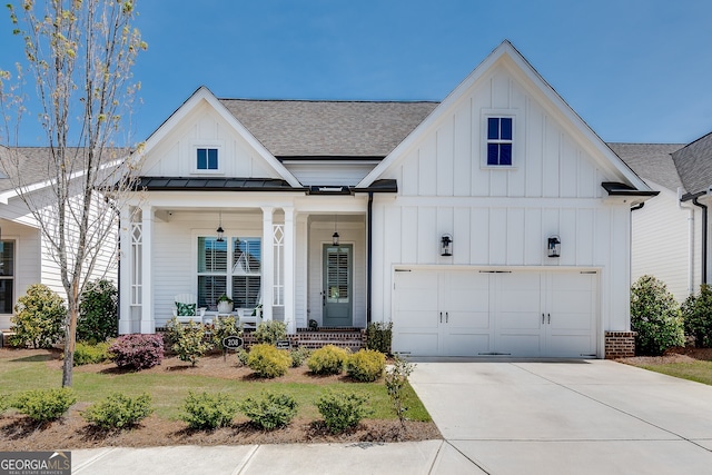 modern farmhouse style home with roof with shingles, a garage, board and batten siding, covered porch, and driveway