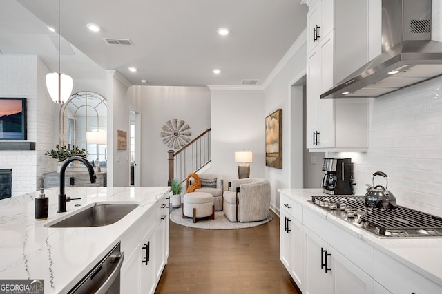 kitchen with visible vents, open floor plan, wall chimney range hood, a sink, and backsplash