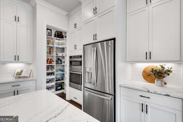 kitchen with white cabinets, light stone counters, stainless steel appliances, tasteful backsplash, and ornamental molding