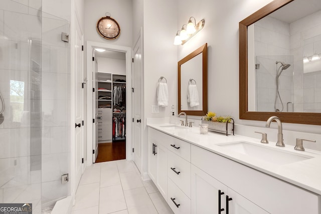 bathroom with a sink, tile patterned floors, a stall shower, and a walk in closet