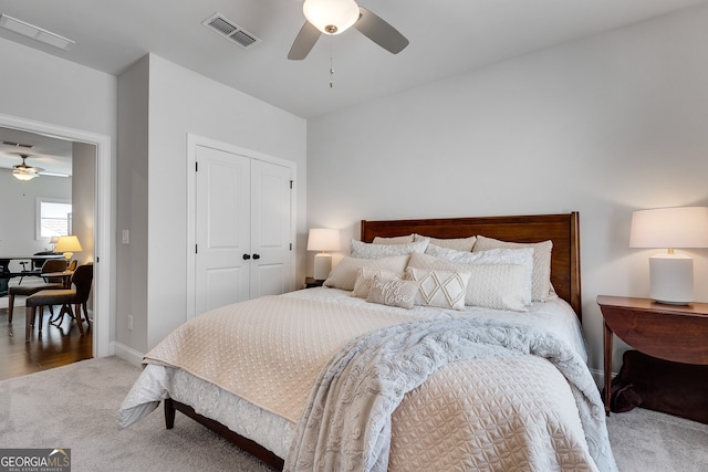 carpeted bedroom with ceiling fan, visible vents, baseboards, and a closet
