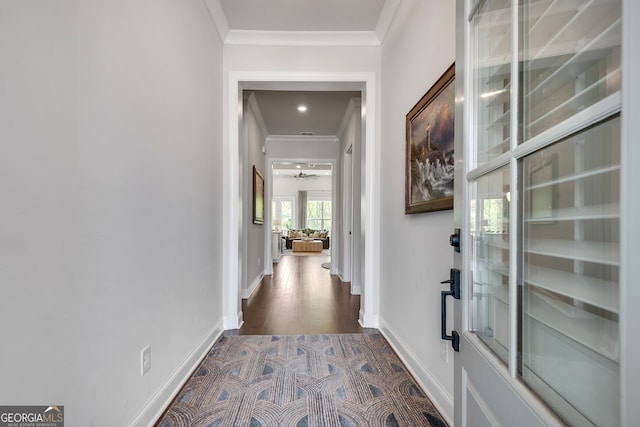 hallway featuring baseboards, ornamental molding, and dark wood-style floors