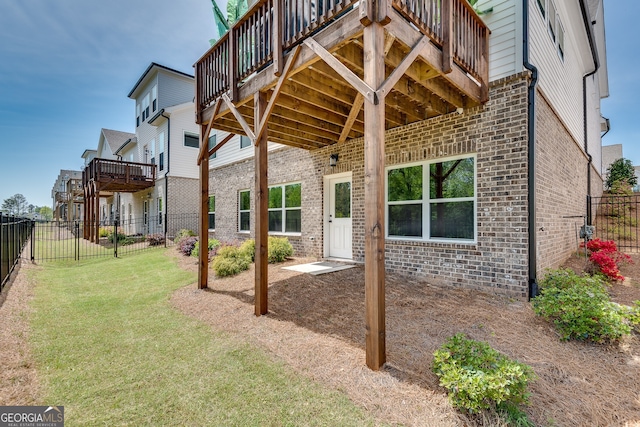 back of house featuring a yard, brick siding, a wooden deck, and a fenced backyard