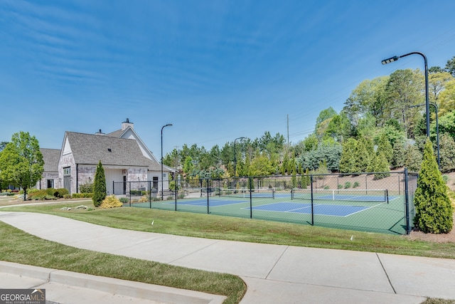 view of basketball court featuring a yard, a tennis court, and fence