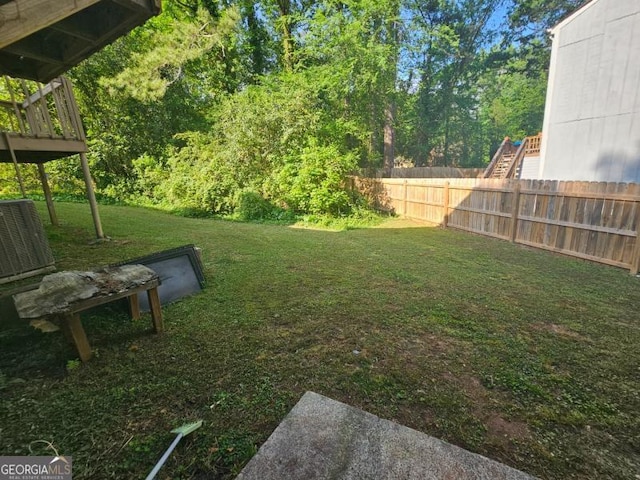 view of yard with fence, central AC unit, and a wooden deck