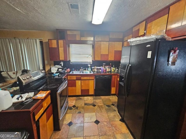 kitchen with a sink, a textured ceiling, brown cabinetry, visible vents, and black appliances