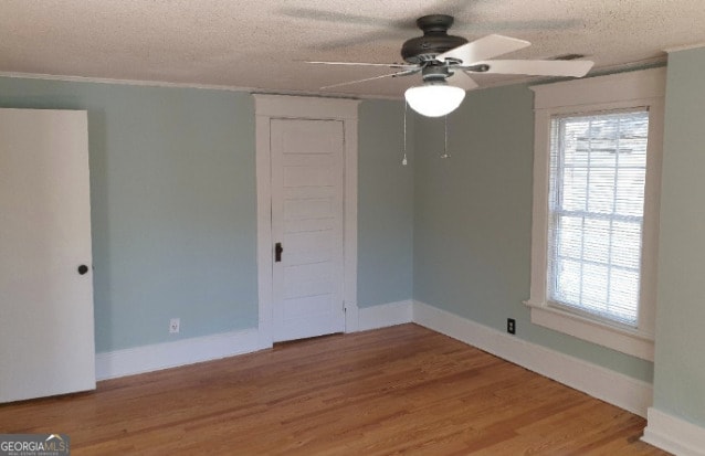 unfurnished room featuring plenty of natural light, a ceiling fan, light wood-type flooring, and a textured ceiling