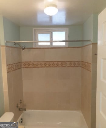bathroom featuring washtub / shower combination and toilet