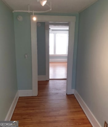 hallway with crown molding, baseboards, and wood finished floors