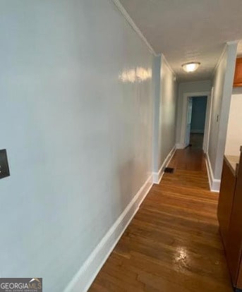 hallway featuring crown molding, baseboards, and dark wood-type flooring