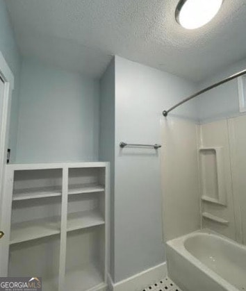 full bathroom with baseboards, tile patterned floors, a textured ceiling, and  shower combination