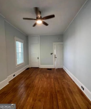 unfurnished bedroom featuring crown molding, a ceiling fan, baseboards, and wood finished floors
