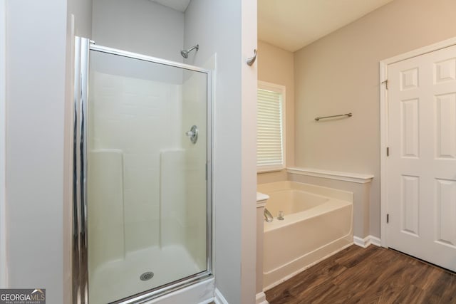 full bathroom featuring a garden tub, baseboards, a shower stall, and wood finished floors