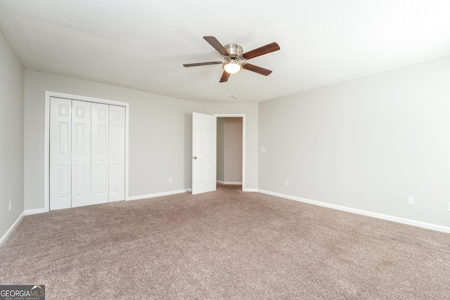 unfurnished bedroom featuring baseboards, carpet, ceiling fan, and a closet