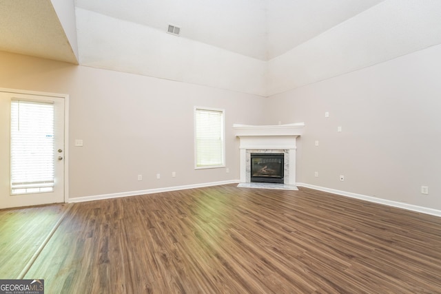 unfurnished living room featuring baseboards, a glass covered fireplace, wood finished floors, and visible vents