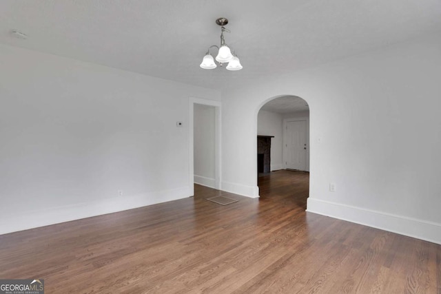 3223 Cleveland Hwy, Gainesville, GA 30506 - unfurnished dining area featuring an inviting chandelier, arched walkways, baseboards, wood finished floors, and a tile fireplace