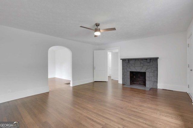 3223 Cleveland Hwy, Gainesville, GA 30506 - unfurnished living room with ceiling fan, arched walkways, wood finished floors, and a fireplace