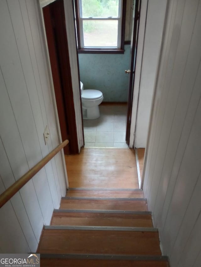 staircase with wooden walls and wood finished floors